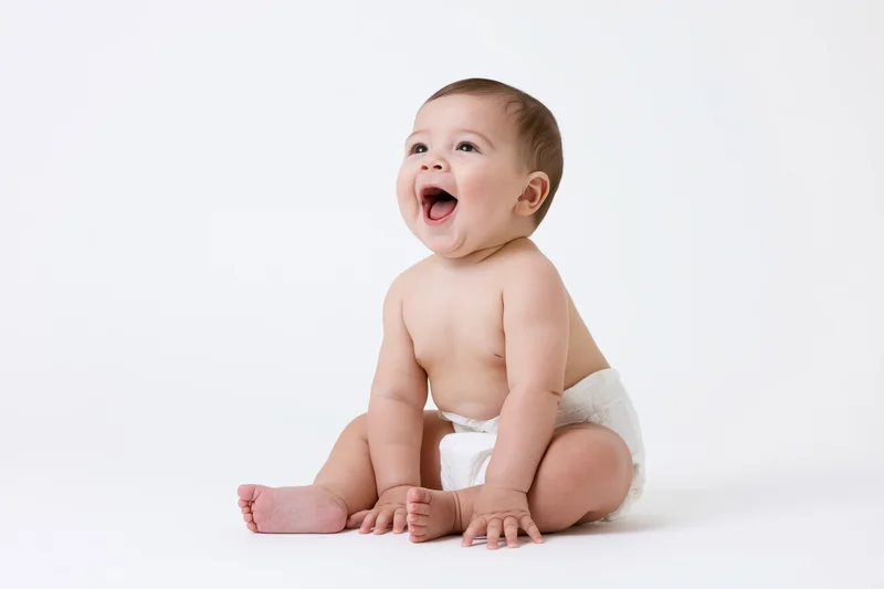 Baby sitting on white backdrop laughing with mouth open