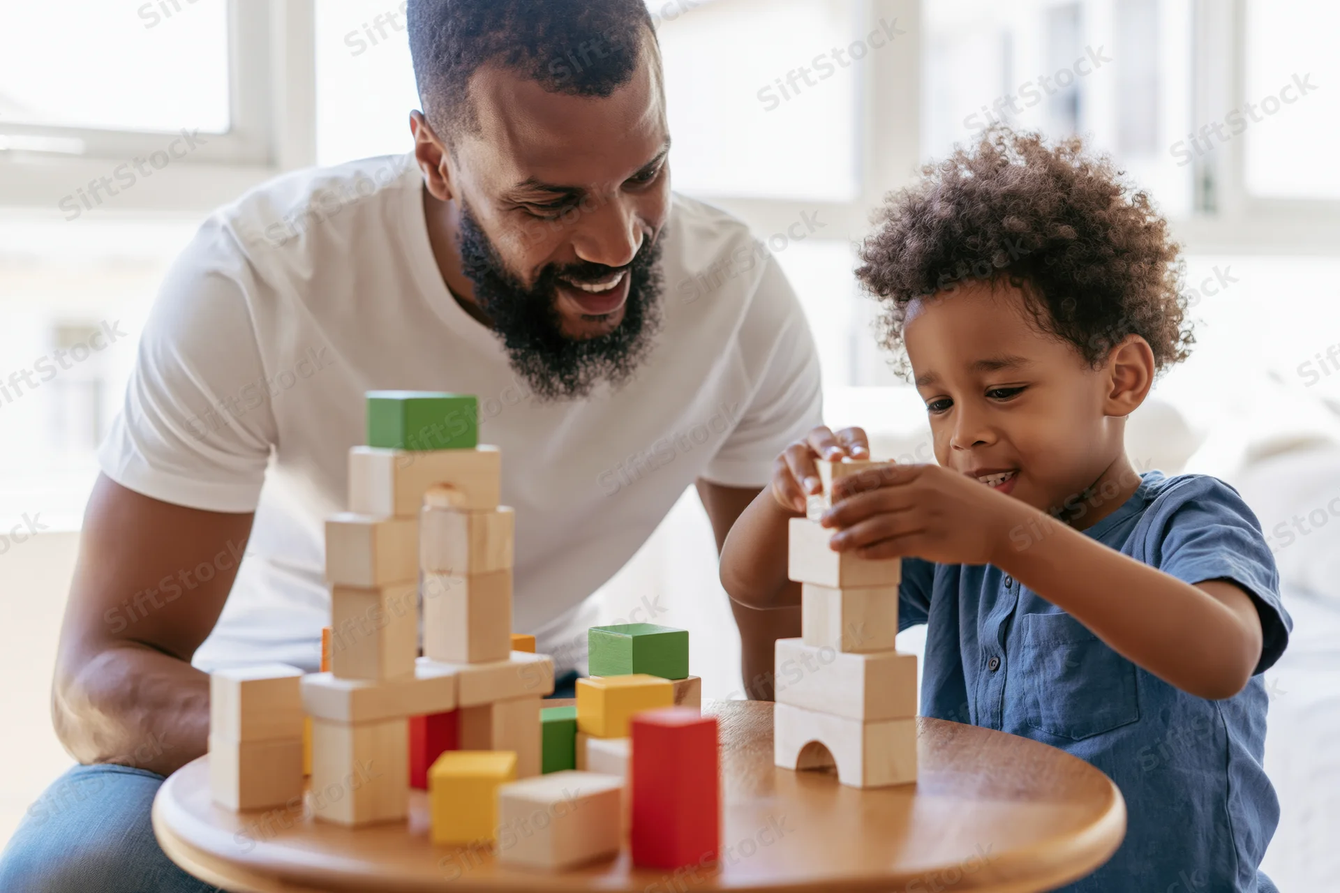 Father and son playing with wooden blocks at a table in a living room
