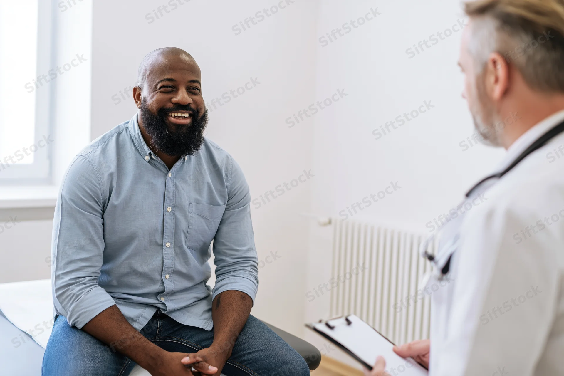 Bearded man smiling during medical consultation with doctor in clinic