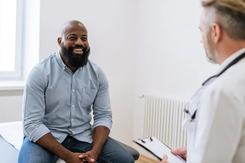 Bearded man smiling during medical consultation with doctor in clinic