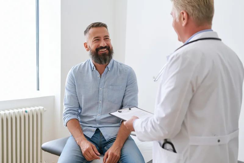 Bearded man smiling during doctor consultation in clinic office