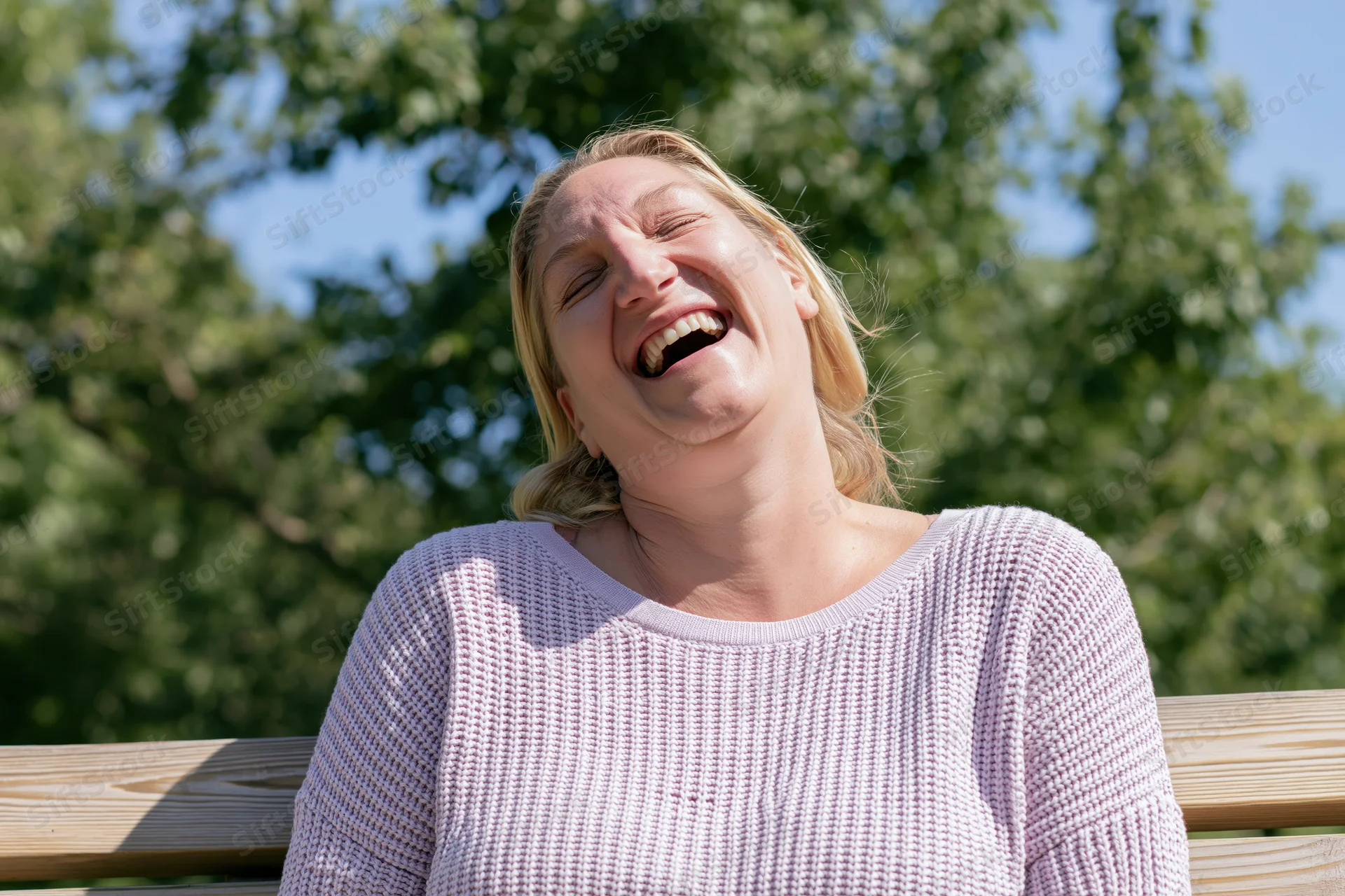 Woman laughing openly on a park bench outdoors