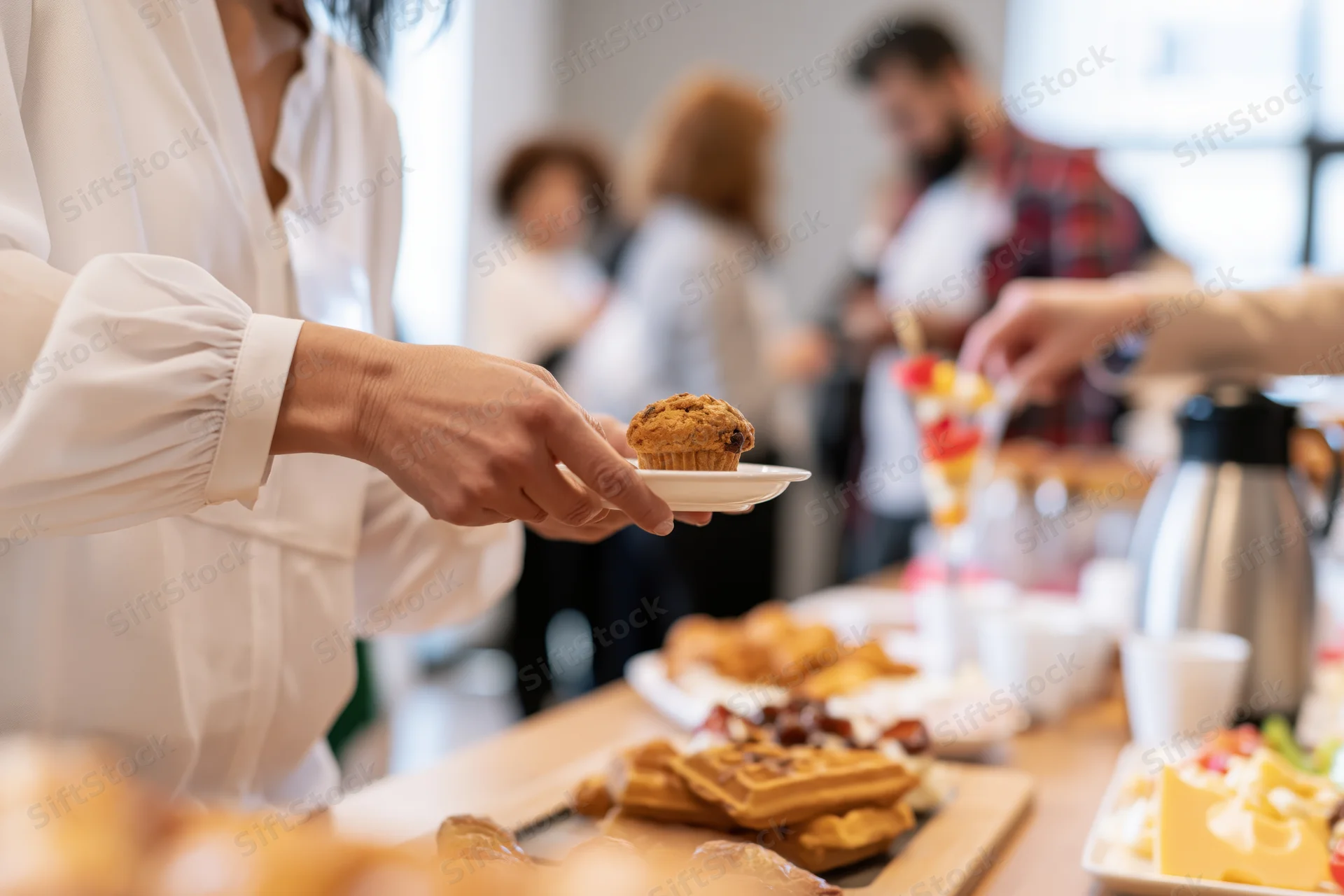 Woman serving a muffin from a breakfast buffet at a corporate event