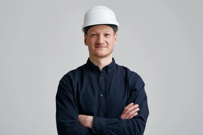 Man in white hard hat with arms crossed smiling in studio portrait