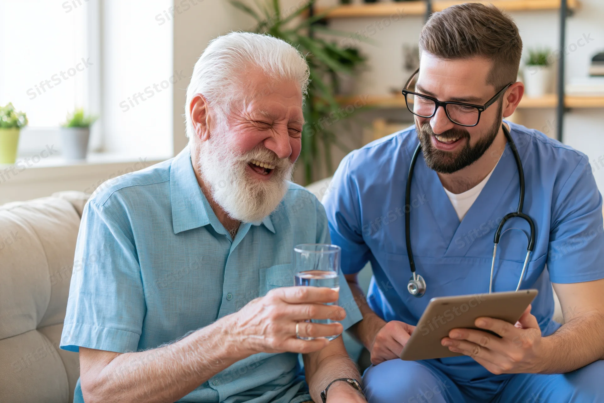 Senior man laughing while holding a glass of water during a home visit with a doctor using a tablet