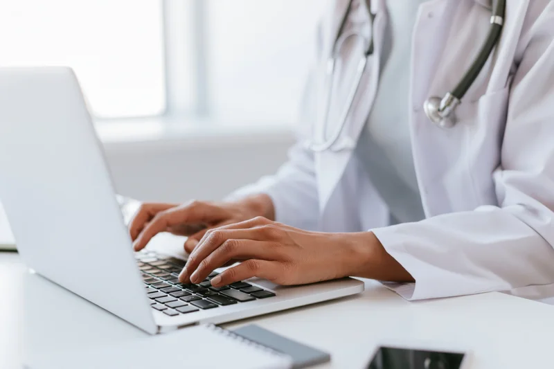 Female doctor typing on laptop at clinic desk