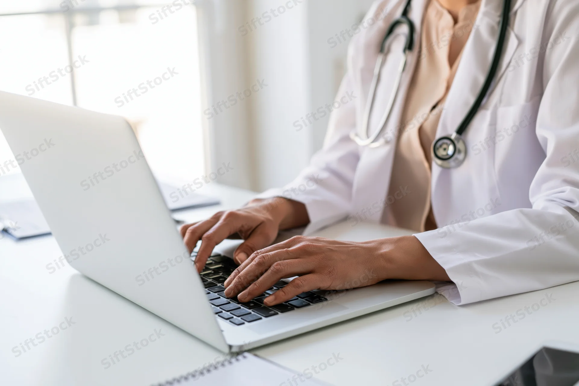 Female doctor typing on laptop at clinic desk