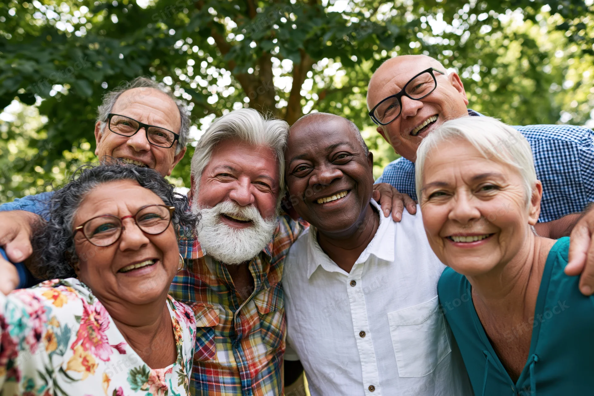 Diverse senior friends smiling together outdoors in a park with arms around each other