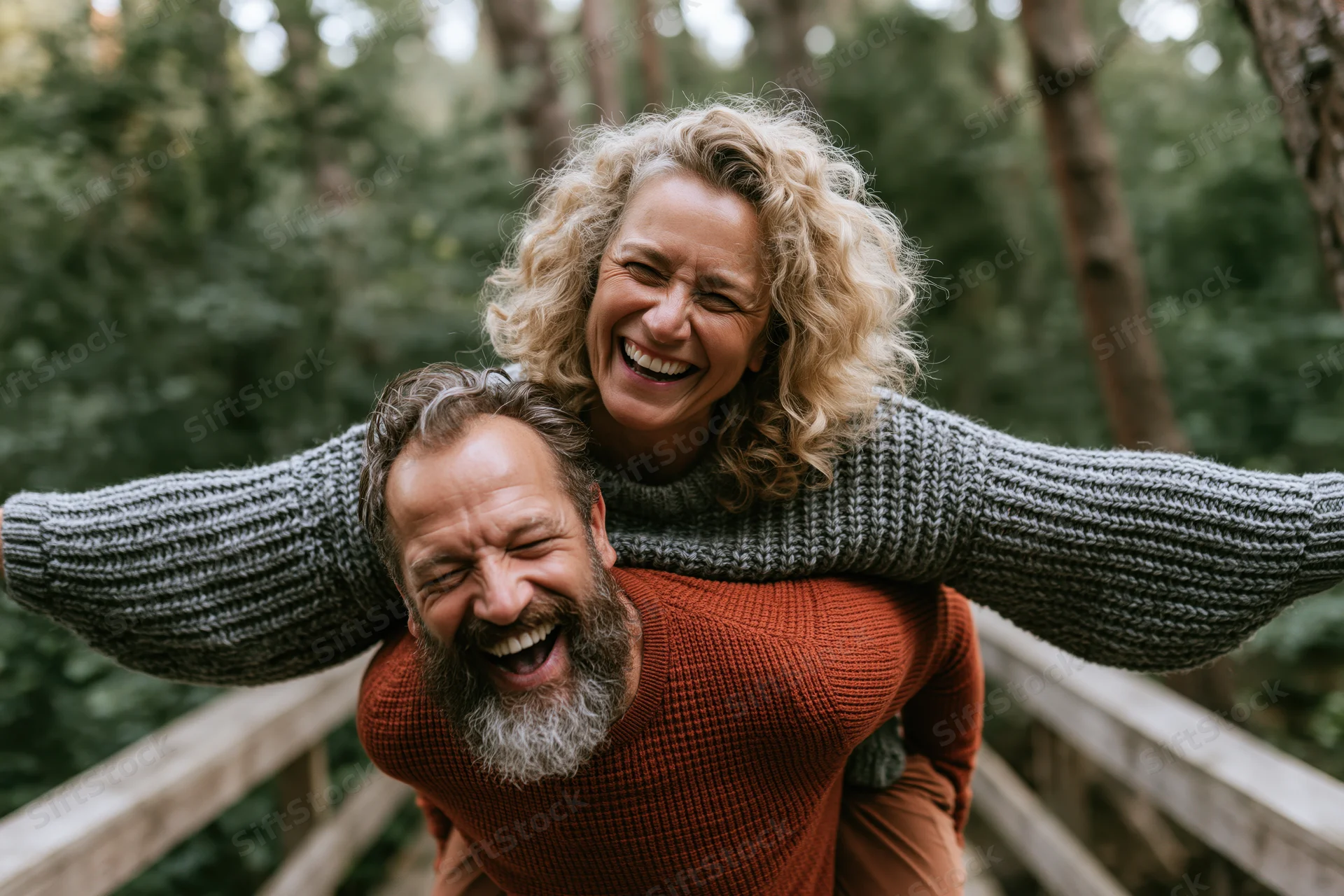 Mature couple laughing while piggybacking on a forest trail