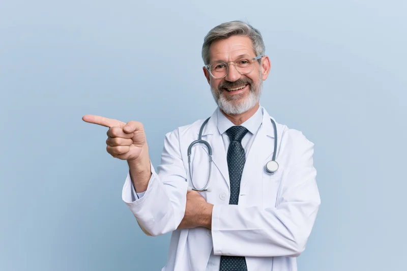 Senior male doctor in white lab coat pointing to the side with stethoscope around neck