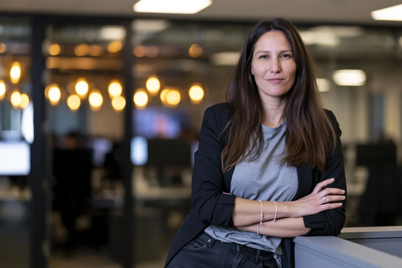 Woman with arms crossed leaning against desk in modern office interior