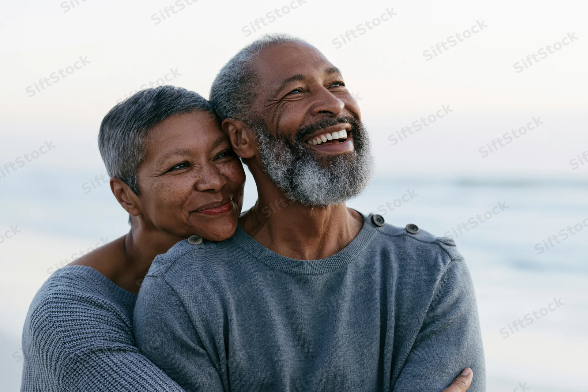 Senior african couple embracing and smiling on a beach at dusk