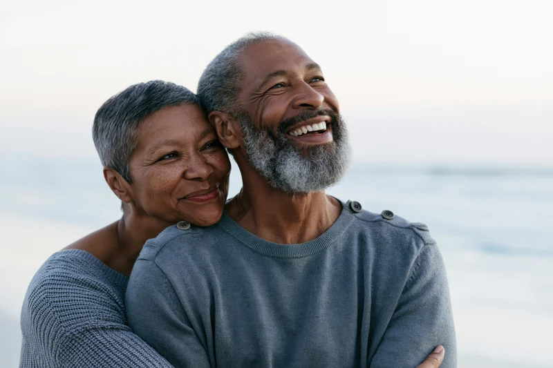 Senior african couple embracing and smiling on a beach at dusk