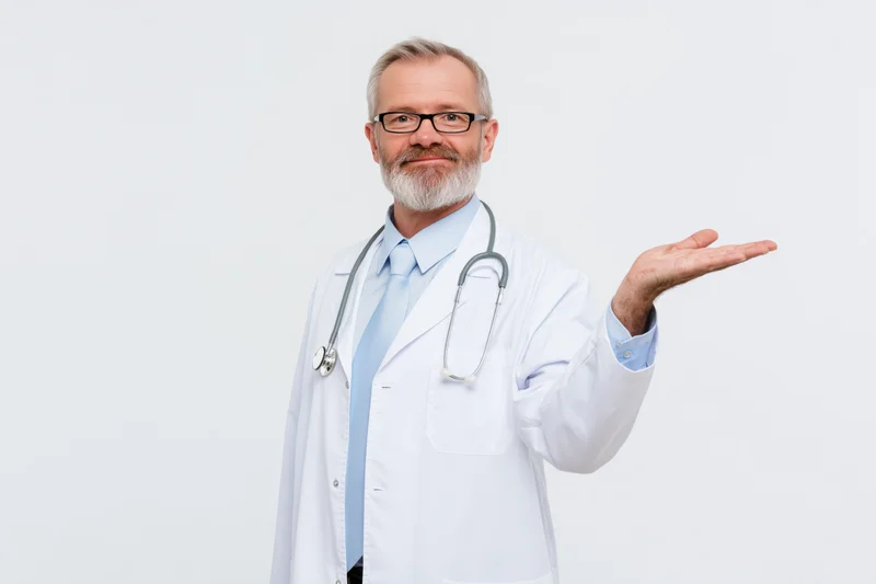 Middle-aged male doctor in white coat with stethoscope gesturing with open hand in studio