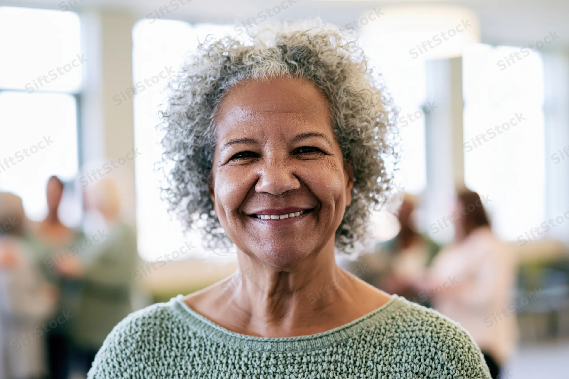 Senior black woman smiling in a knit green sweater in an office setting