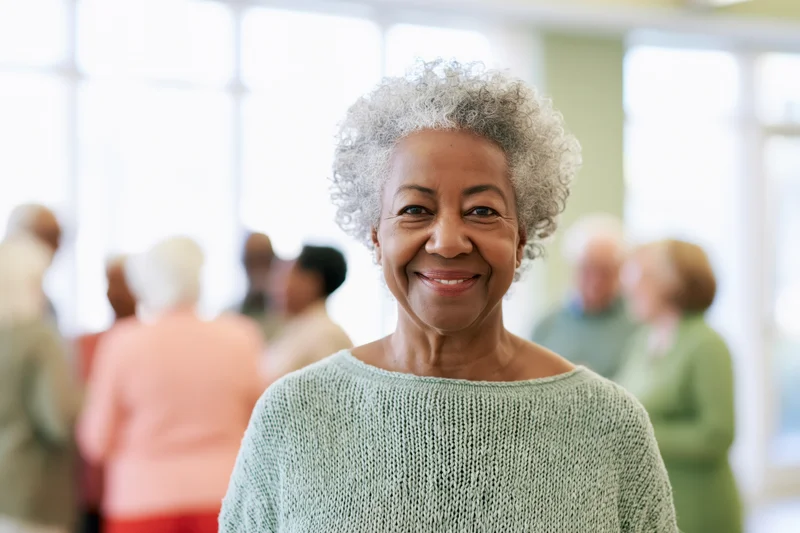 Senior black woman smiling in a knit sweater at a community gathering