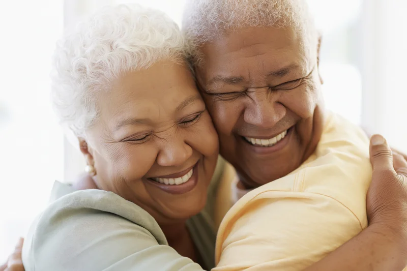 Senior african american couple embracing cheek to cheek smiling warmly indoors