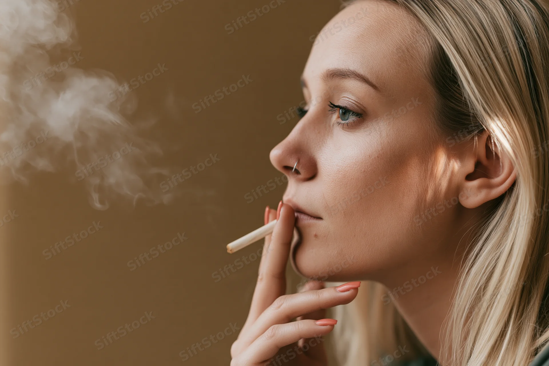 Young blonde woman exhaling cigarette smoke in profile view