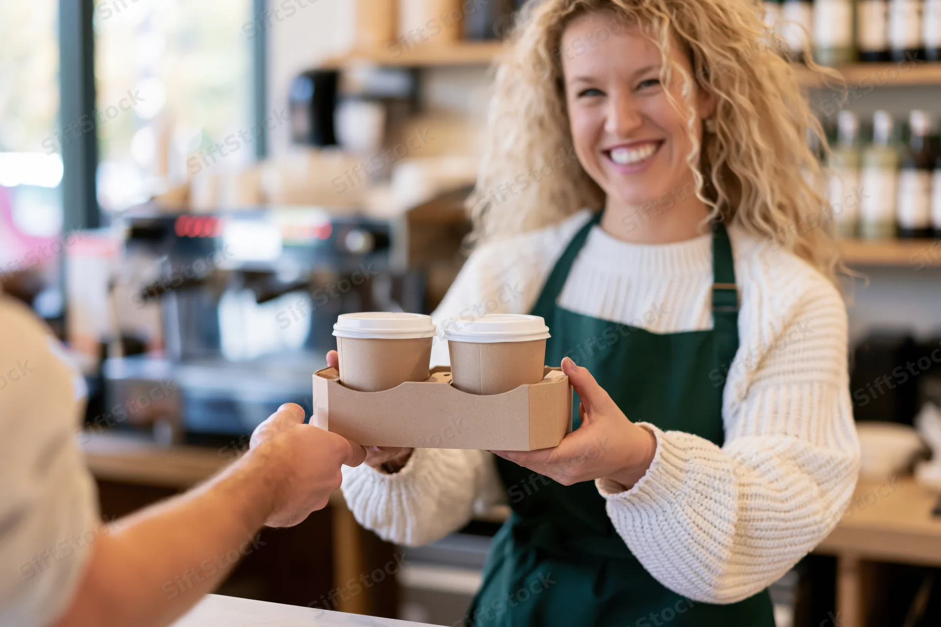 Smiling young woman barista handing coffee cups to customer at cafe counter