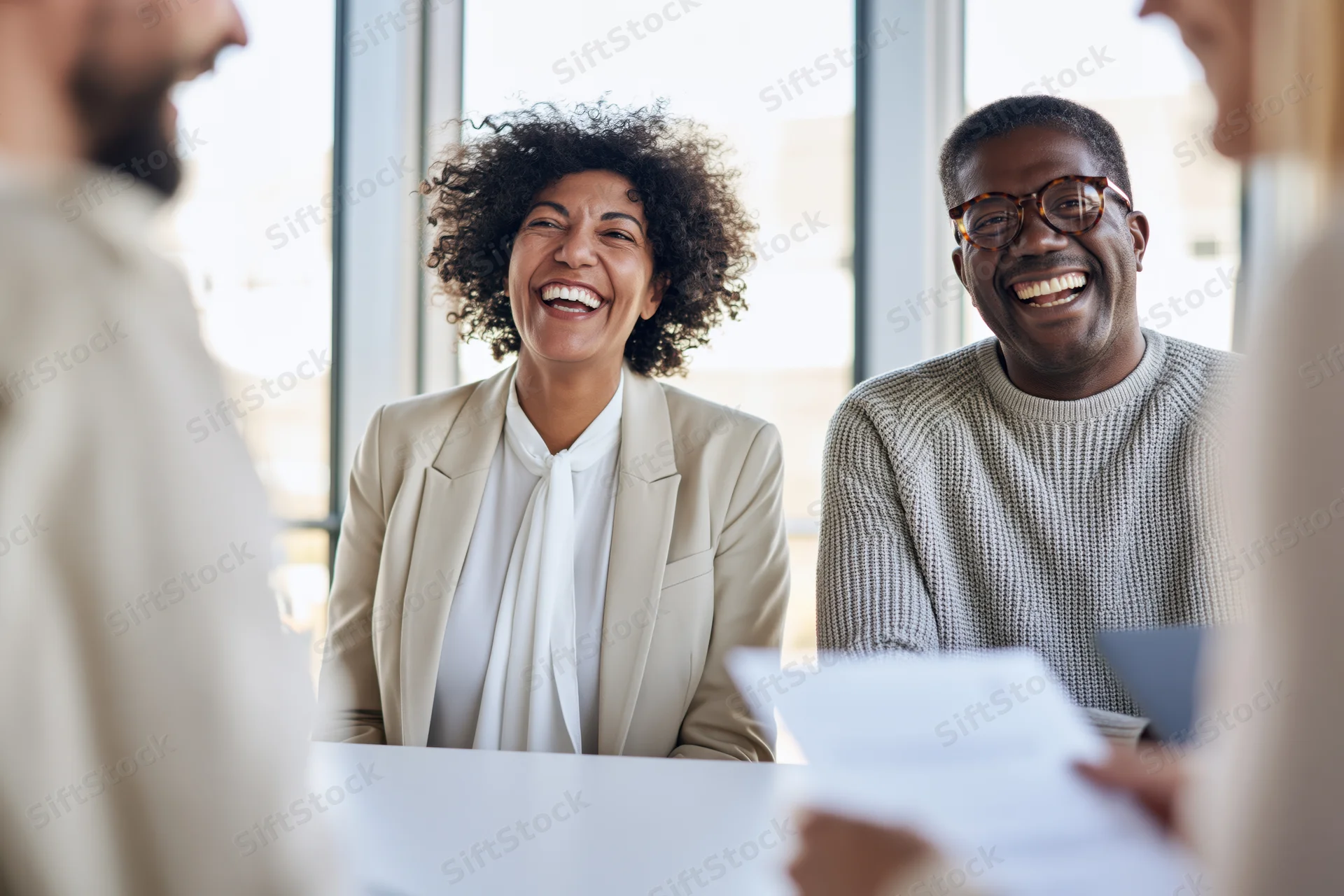 Coworkers laughing together during a meeting in a bright office space