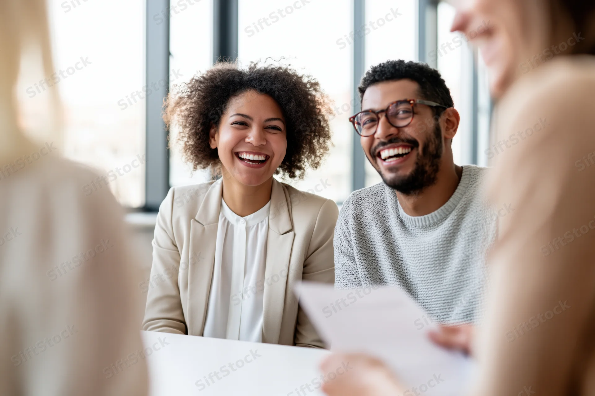 Coworkers laughing together during a casual meeting in an office setting