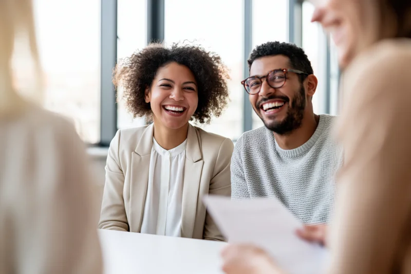 Coworkers laughing together during a casual meeting in an office setting
