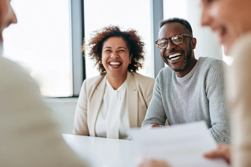 Coworkers laughing together during a casual meeting in an office setting