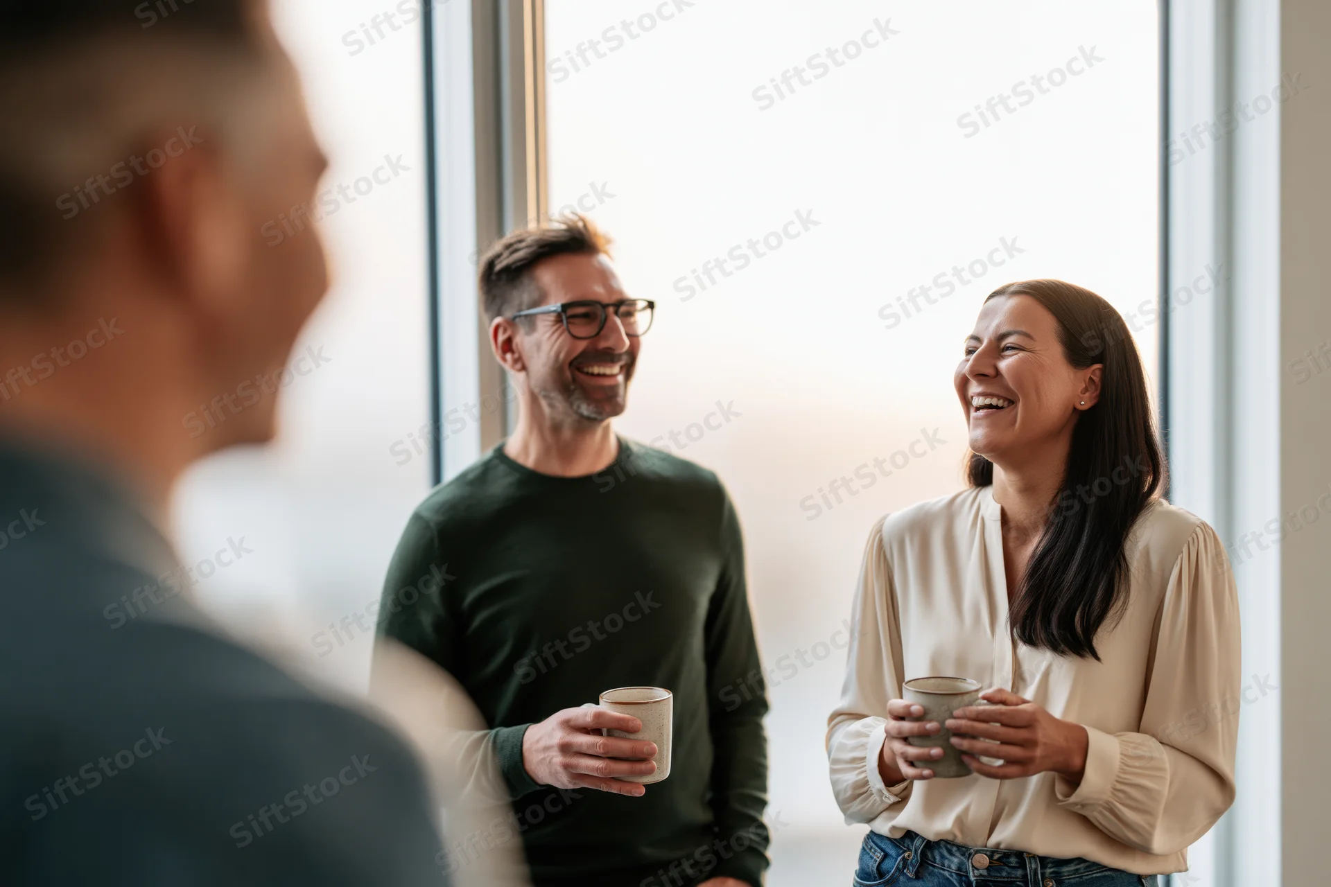 Coworkers laughing together during coffee break in office