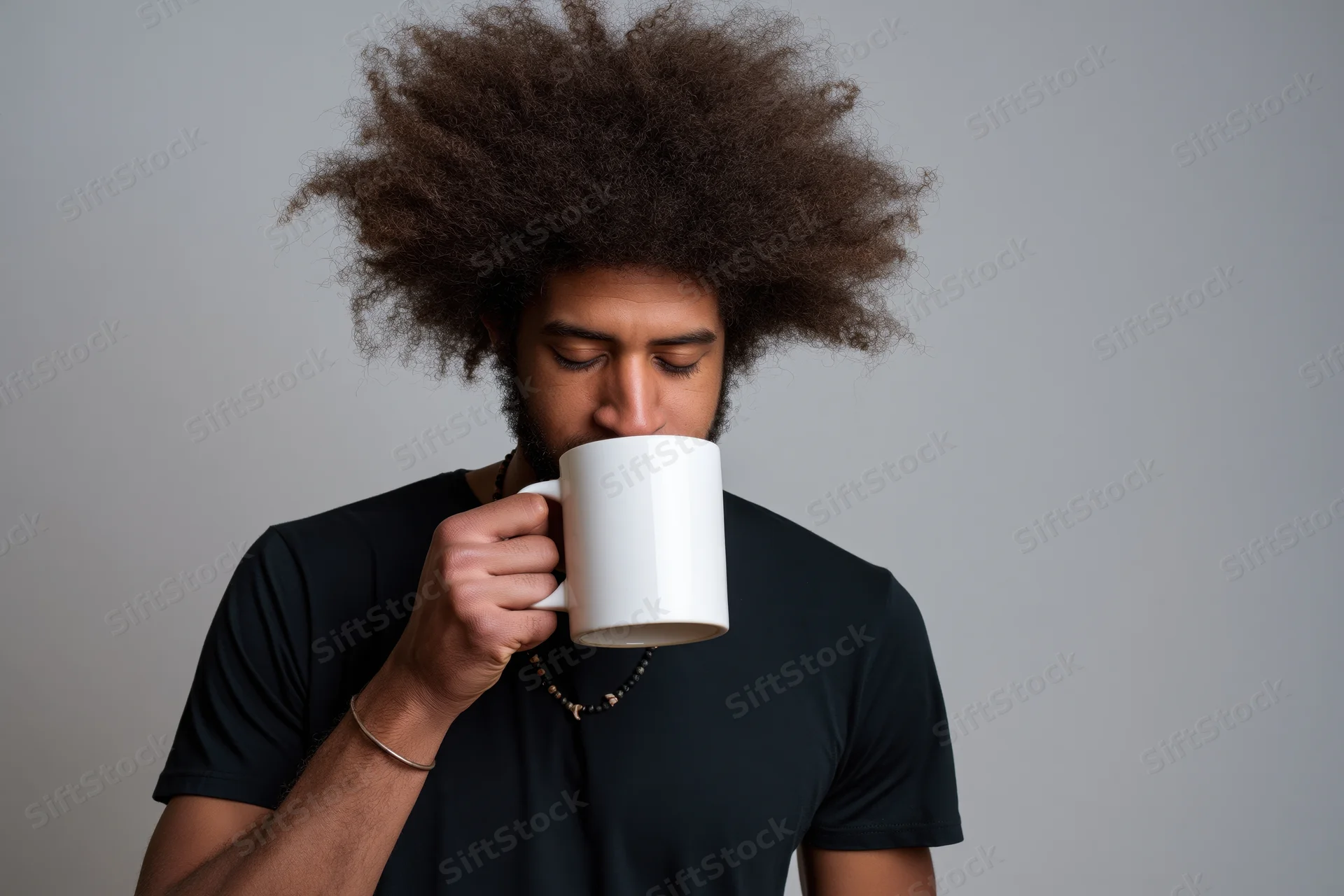 Young black man with afro drinking from oversized white mug in studio portrait