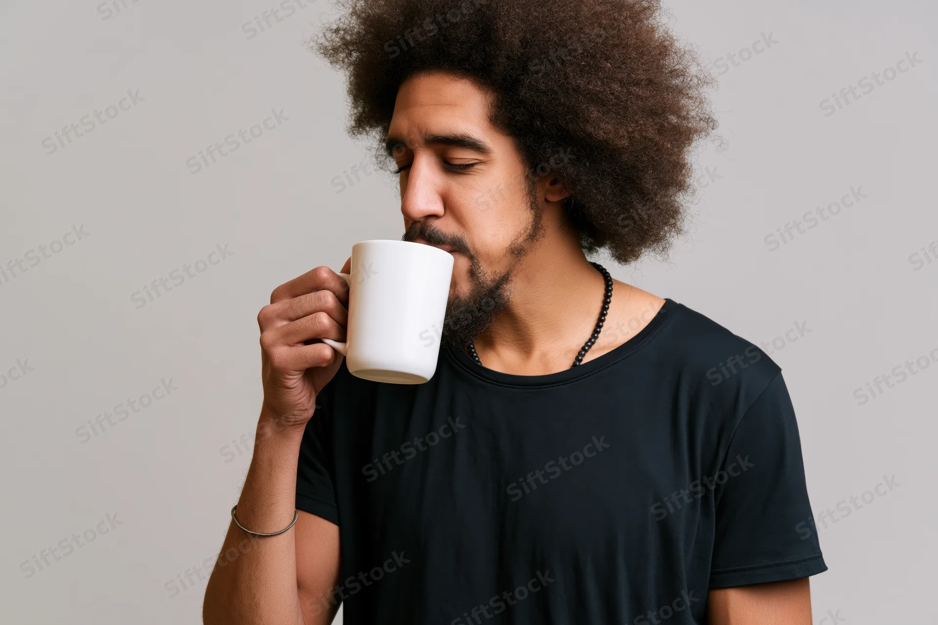 Young black man with afro drinking from a white mug in a studio setting