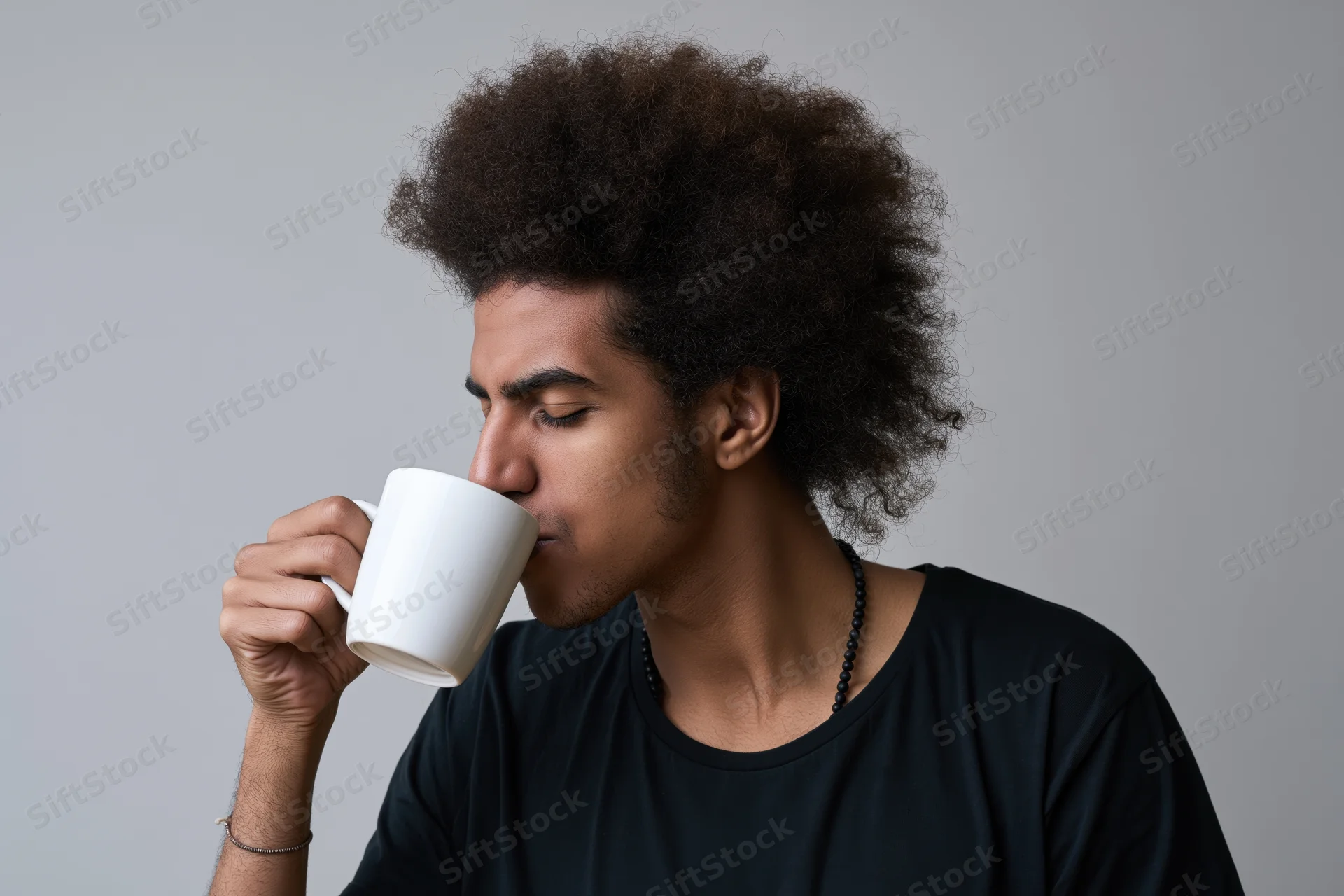 Young black man with afro drinking from oversized white mug in studio portrait