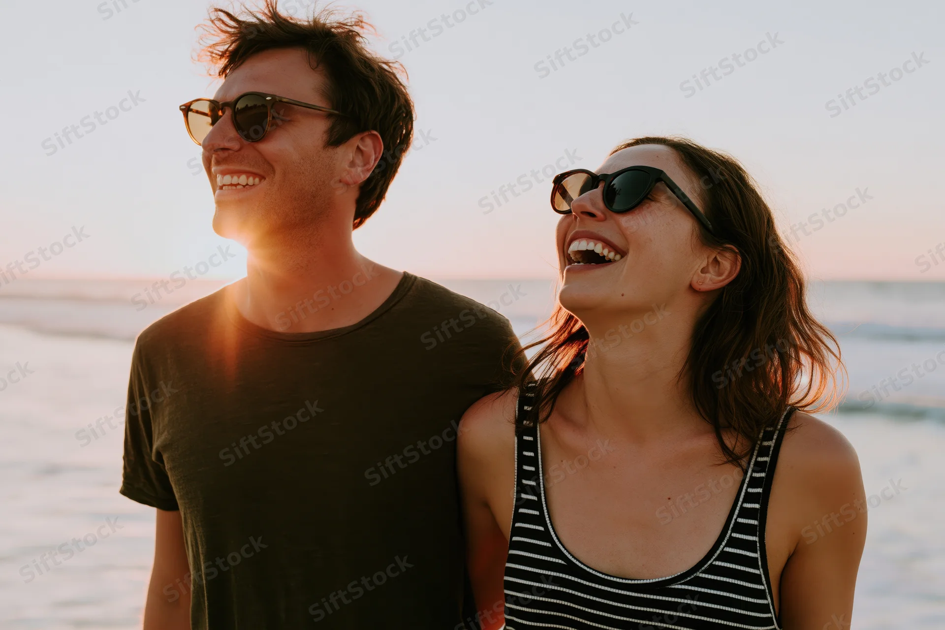 Couple laughing together on beach at sunset