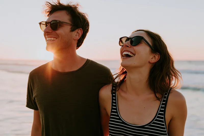 Couple laughing together on beach at sunset