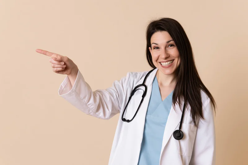 Woman in white lab coat pointing left while smiling in studio setting