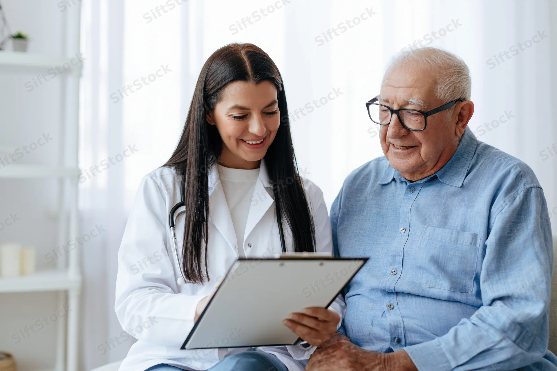 Young female doctor consulting with senior patient in clinic, holding clipboard and smiling