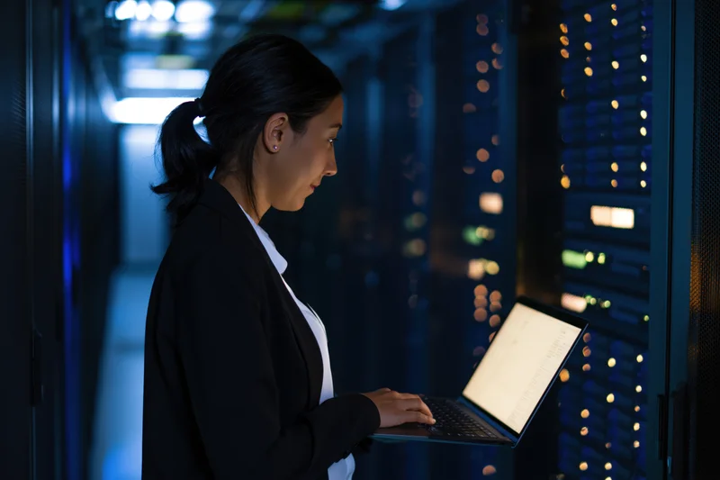 Woman it technician using laptop in server room