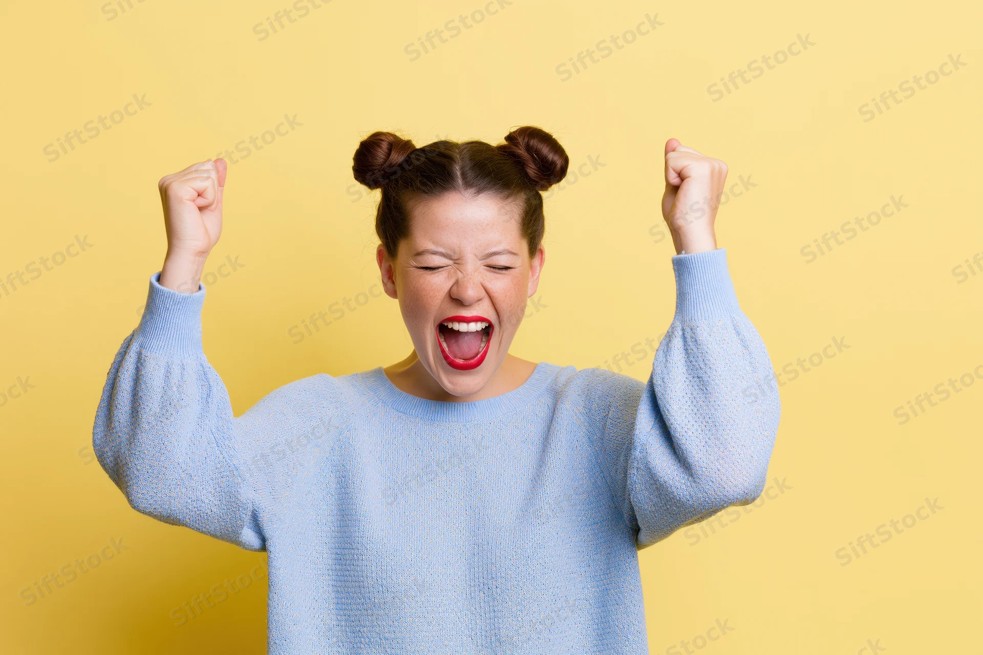 Woman celebrating with fists raised and eyes closed against yellow background