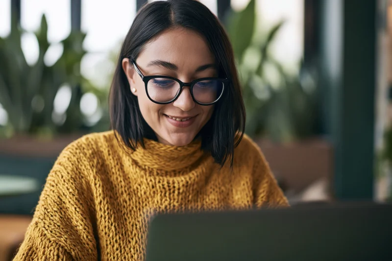 Woman smiling while working on laptop in office setting