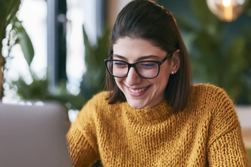 Woman smiling while working on laptop in modern office space