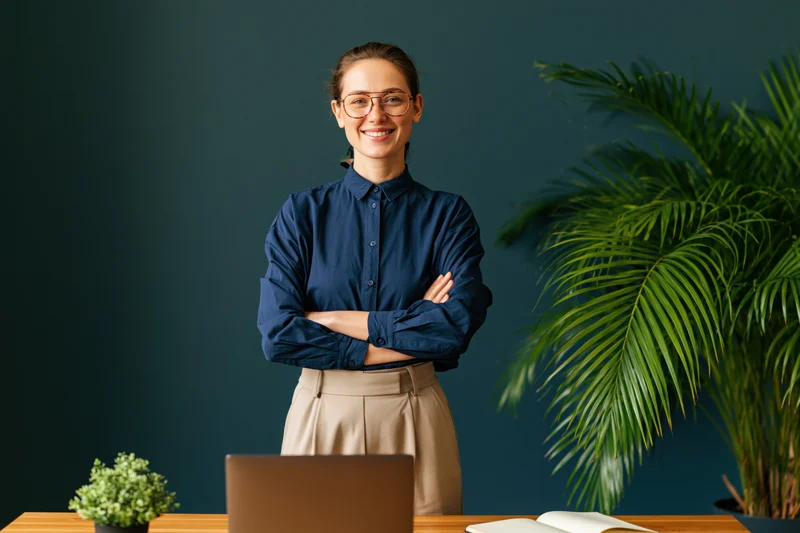 Woman standing behind desk with arms crossed in office setting