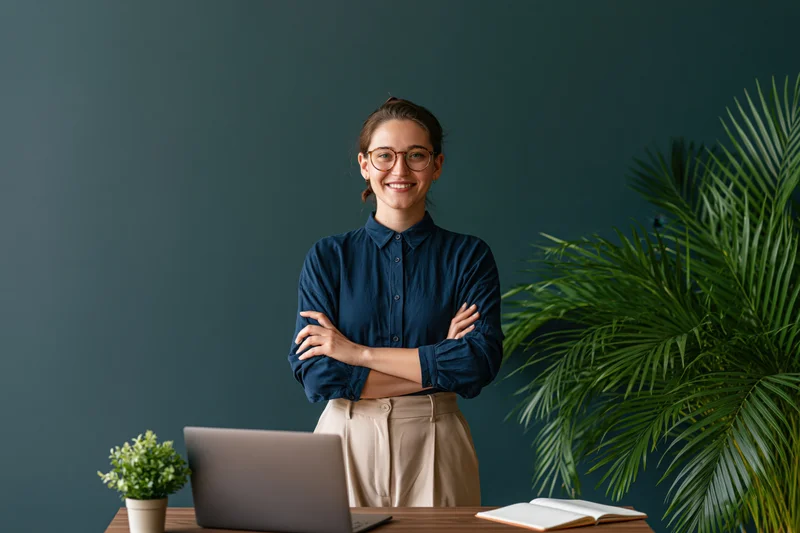 Woman standing behind desk with arms crossed in office workspace