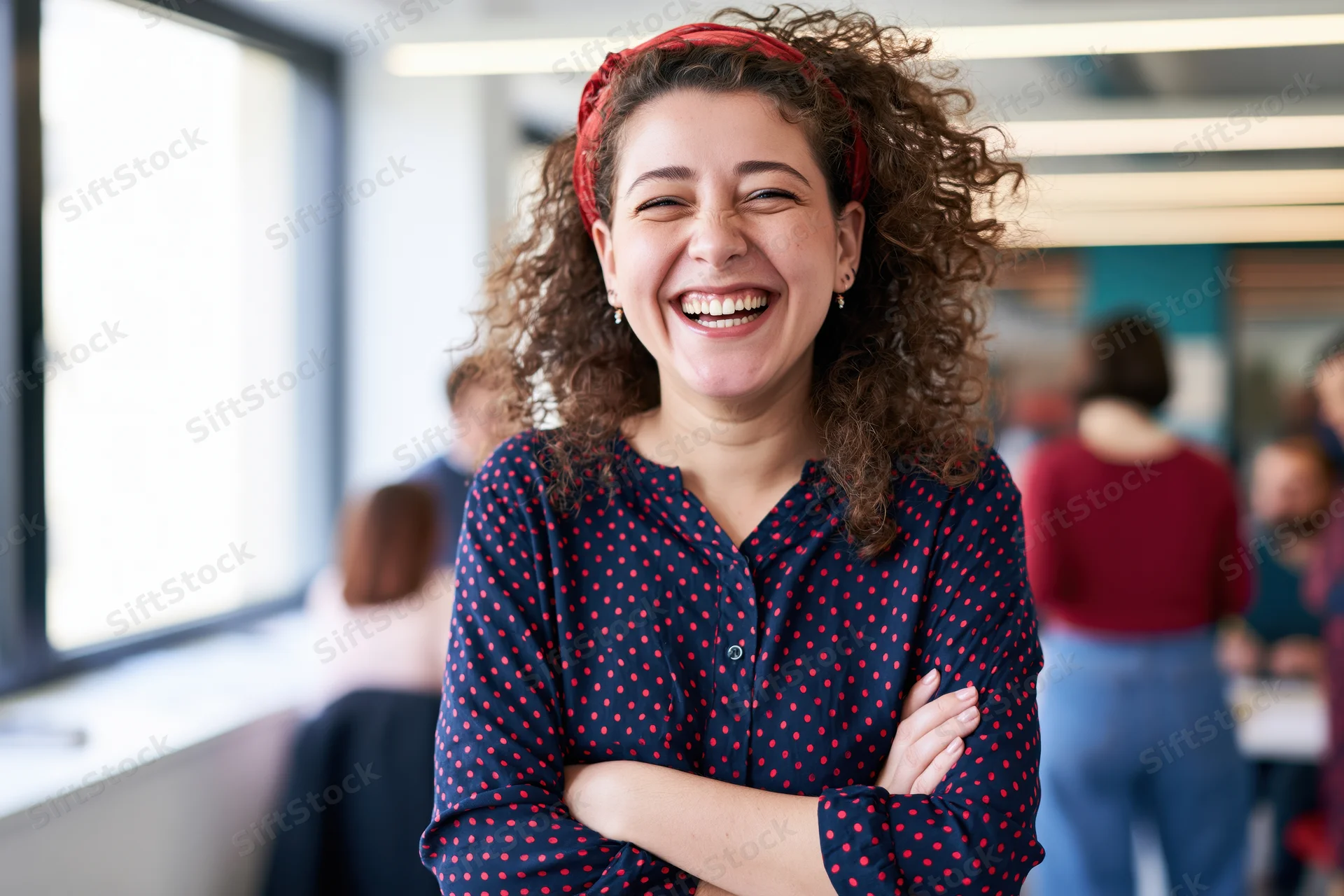 Young woman laughing with arms crossed in an office setting
