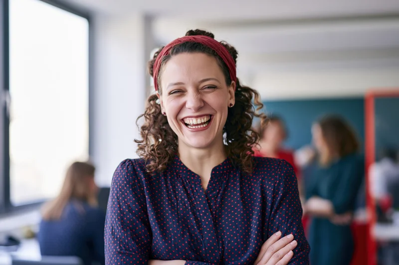 Woman laughing with arms crossed in office setting