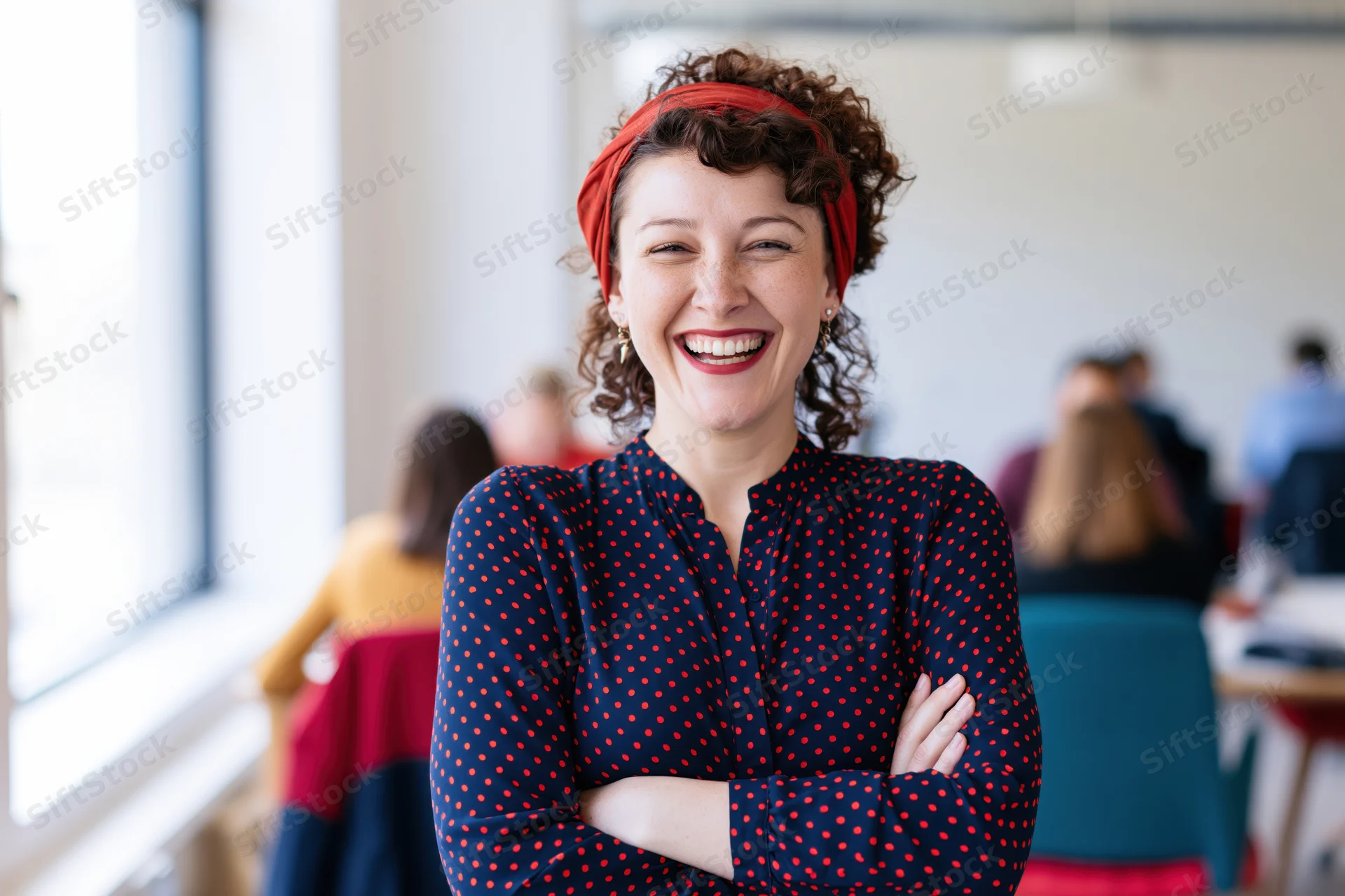 Woman laughing with arms crossed in office setting