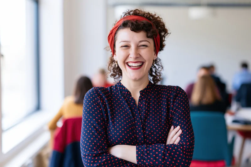 Woman laughing with arms crossed in office setting