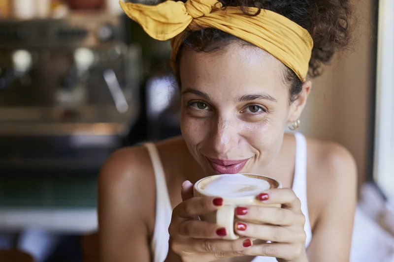 Woman smiling while holding a latte cup in a cafe