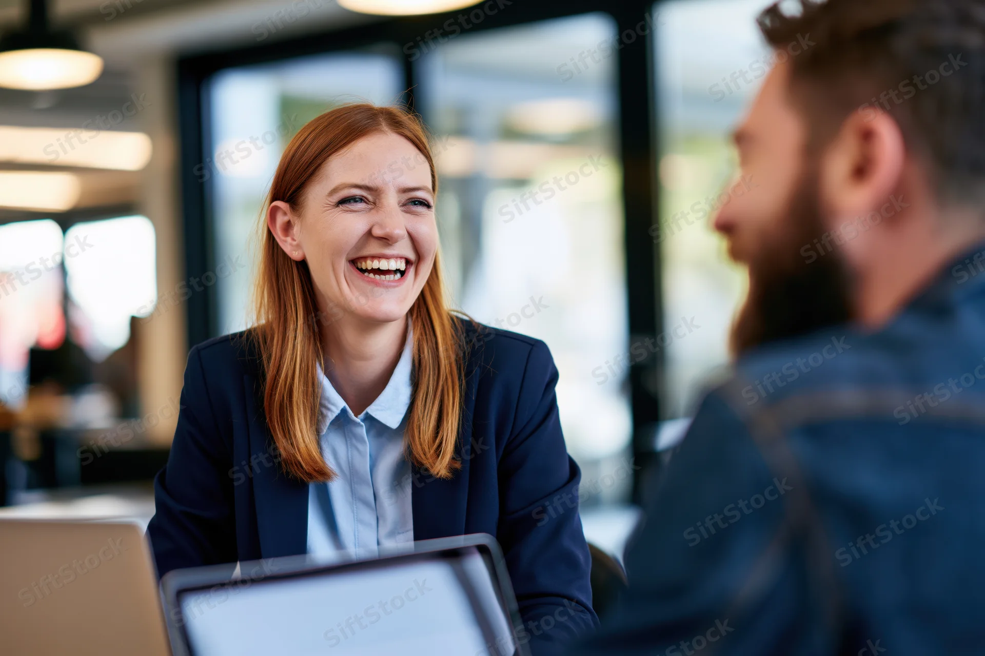 Woman laughing during a business meeting in an office setting