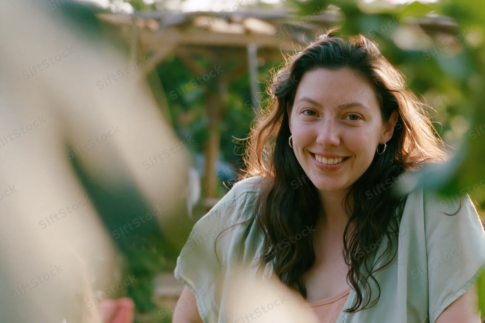 Young woman smiling warmly in a garden surrounded by green foliage