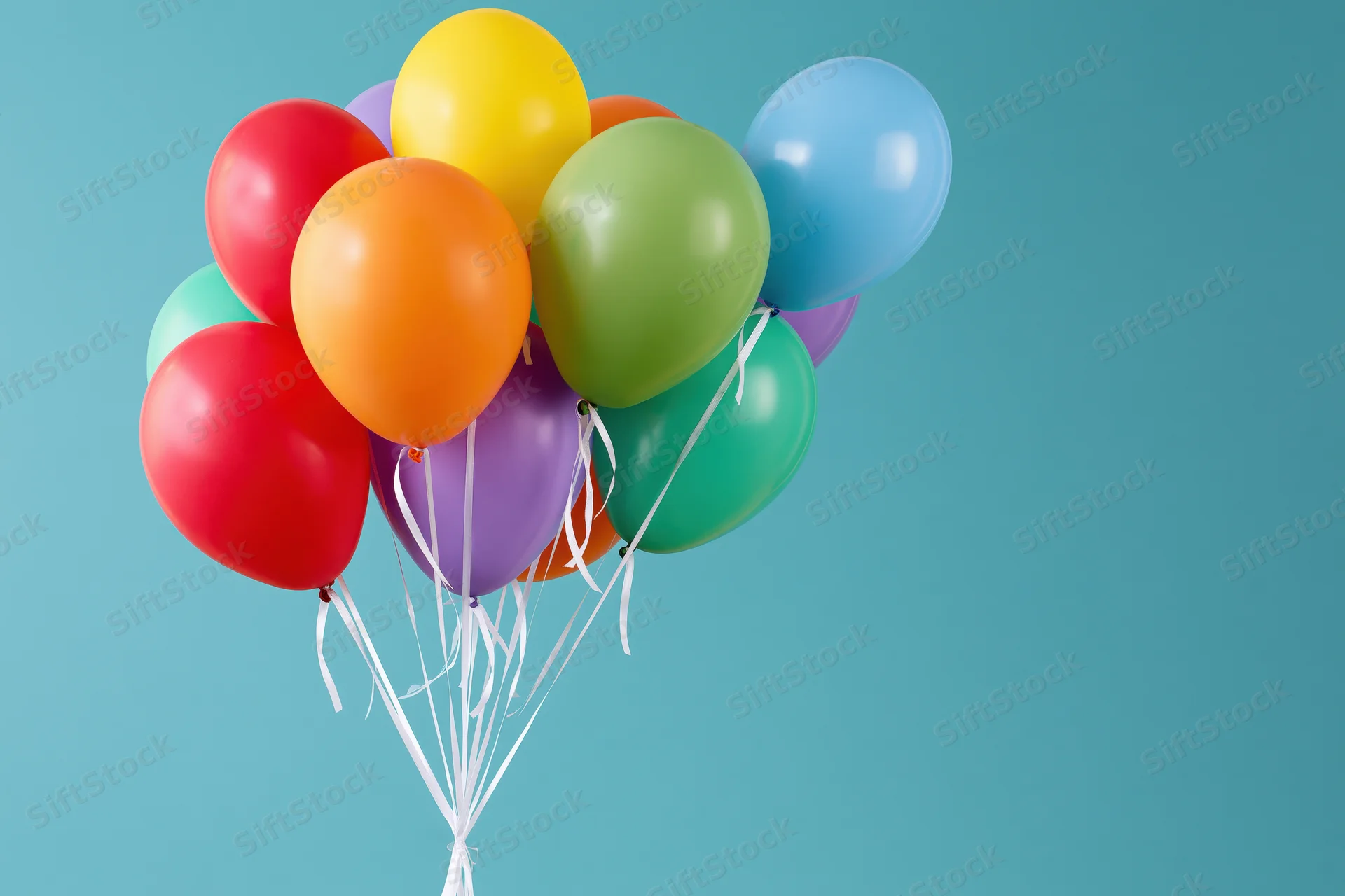 A cluster of colorful latex balloons tied together with white string against a teal background