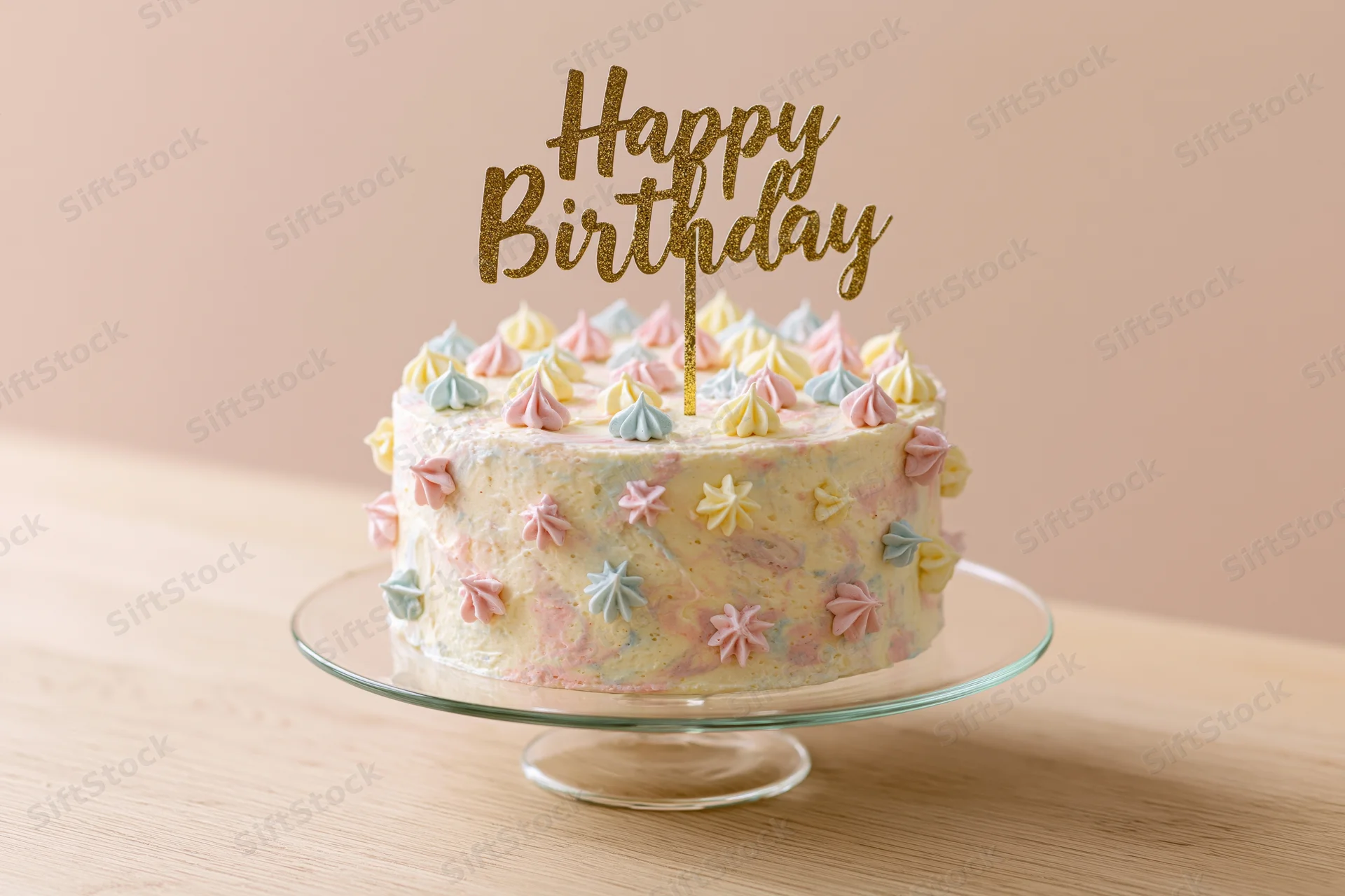 Decorated birthday cake with gold glitter topper on glass stand on wooden table